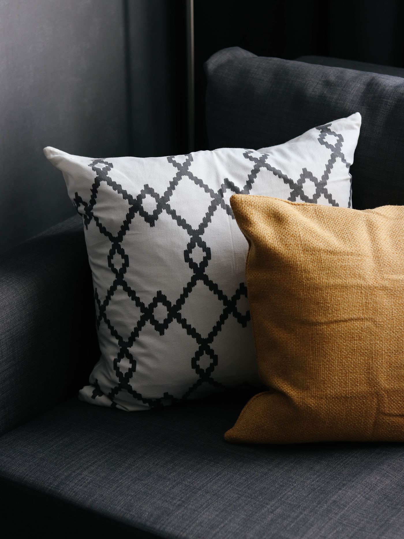 Mustard and geometric patterned cushions on a charcoal sofa